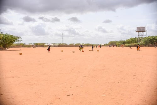 A wide view of refugees rolling water jerricans on the ground from a water point in Dagahaley camp.