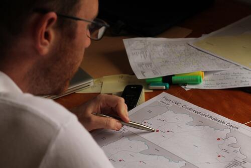 Pierre Vernier, GIS-Officer (Geographical information systems officer) is studying one of his produced maps about the origins of confirmed and probable patients in the Foya Ebolat management center