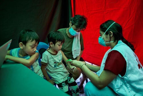 Agustina and her grandson Clark watch as Trisha Thadhani, MSF TB doctor, conducts a medical evaluation of her other grandson, Ion, at one of MSF's active case finding sites for tuberculosis on March 13, 2023 in Tondo, Manila, Philippines.