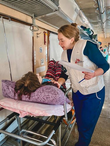 Medical doctor, Nataliia Pyvovar, checks on a patient onboard the MSF medical evacuation train.

On 20 and 22 October 2023, MSF evacuated 150 patients from Kherson region after the hospital was shelled. Patients were transferred to other health facilities around Ukraine.

"Doctors and nurses have to communicate with each patient, explaining where they are going and why," says MSF doctor, Nataliia Pyvovar. "People asked me if it would be safe at their new destination and if they would return."