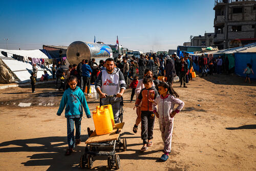 Youssef Al-Khishawi, an MSF water and sanitation agent, helps children carry water to their tent in the Tal Al-Sultan area of the southern Gaza town of Rafah, on January 27, 2024.
He says: “In a normal situation, one person needs two to three liters of drinking water per day. Now, with the current shortage, the average for one family of six is one gallon of water (3.8 litres).” 

“The main challenge we face in distributing water is the lack of fuel to pump and transport it,” says Al-Khishawi. “The second is the lack of proper roads for our trucks to drive on, because there are tents even on the asphalt. The third is that there are no water distribution points – even they have been bombed. Water pipes, streets and infrastructures are destroyed.”
