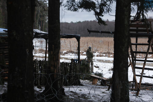 A Polish soldier in his camp, between an observation pulpit and a wooden hut.