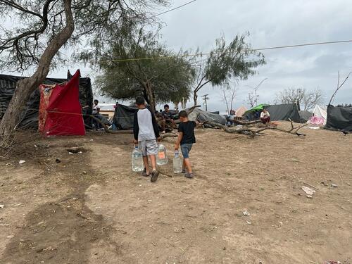 Two children carry drinking water collected from one of the tanks set up by MSF at the informal migrant camp on the edge of the Rio Bravo that separates Matamoros, Tamaulipas, from Brownsville, Texas.