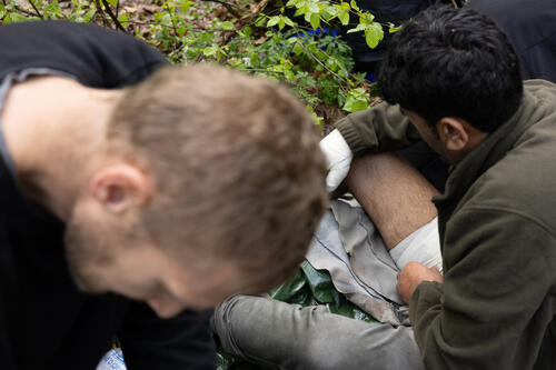 A paramedic is dressing a deep cut wound near the migrant's femoral artery. Such wounds are often sustained when jumping over a 5-meter fence topped with razor wire.