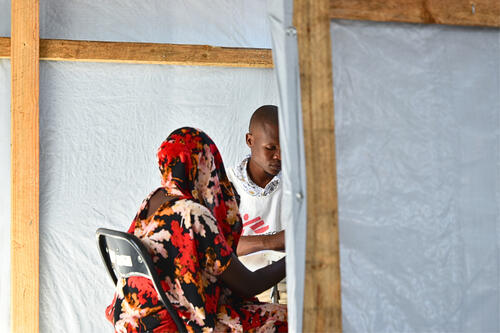 Elvis Badaso, a nurse, during consultation with a patient at Garsen high school medical outpost