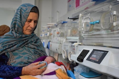 Reza Gul, 60, holds her prematurely born grandson and feeds him milk from a bottle in the neonatal ward at the MSF-supported Mazar-i-Sharif Regional Hospital in Balkh province on 6 January 2025. Reza Gul says her daughter gave birth to triplets two weeks ago at a private health clinic, but all three babies were born several weeks premature and weighed less than one kilogram each. The private doctor referred them to the regional hospital, where the infants stayed under close observation until they gained enough weight to be discharged. The 23-day-old baby boy is the last of his siblings left in the hospital. His two sisters were already discharged, having gained enough weight to go home earlier in the week.