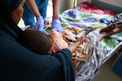 An MSF nurse provides emergency care to a malnourished child at the MSF-supported Bay Regional Hospital in Baidoa as the mother holds her child during treatment.