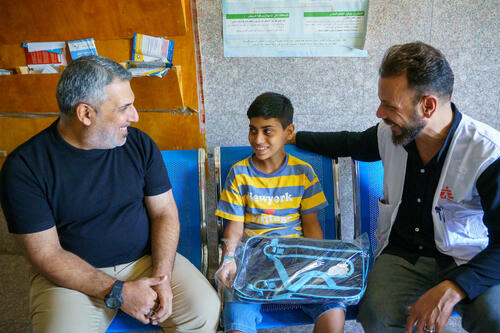 Abu Al-Fadl, a young boy diagnosed early with tuberculosis, sits with his father and an MSF health promoter at Mustafa Al-Adhari Health Center in Sadr City. After completing his treatment, he has recovered and will soon return to school.