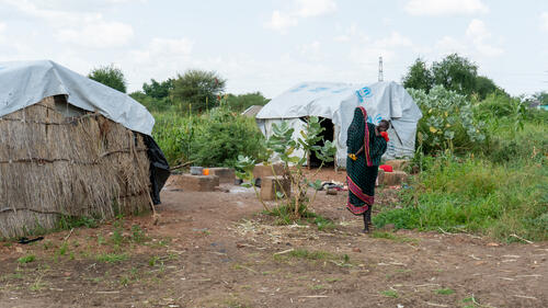 Carrying her baby in her arms, Touma walks across the camp to visit a neighbour. Daily life continues in small, connected steps.