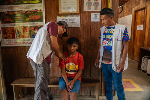 Dr. Carlos Camacho, an MSF medical doctor, and Apalessio Sanöma Ye’kwana, an MSF intercultural mediator, during a medical examination with a boy from the Fuduuwaaduinha community. All activities are carried out with the support of intercultural mediators—community members who speak both languages and help bridge communication between medical teams and patients.