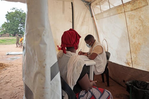 Maria João, a displaced person from Memba District, receives a medical consultation at an MSF mobile clinic in Alua Velha, Eráti District, Nampula Province.
Her health has deteriorated due to injuries from fleeing and possible infections, while her children, aged 10 and 13, face dietary and health challenges. Despite seeking medical help, the local clinic lacked medicines.

Maria fled attacks carried out by a Non-State Armed Group active in Norther Mozambique. She arrived in Alua Velha with her husband and two children, having escaped gunfire and destruction in her home village of Necoro, in Memba district. They walked 25 km before taking a motorbike to reach safety. Initially, they lived under a mango tree for five days before moving into her husband’s family home, which is now overcrowded with 15 people and insufficient resources. In Necoro, she sold mahewe (a fermented beverage made from corn flour, water and sugar) but her house and freezer where she stored the beverage were burned, and her husband’s motorbike was destroyed.

She reports being too frightened to return to Necoro, where violence, including beheadings and arson, has displaced her four times since 2024. 

Although she sometimes helps with farming in Alua Velha, she has no clear plans for the future and lacks the means to rebuild her life. The conflict has impacted her health, food security and finances, leaving her with no belongings or prospects.