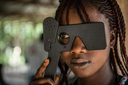 24 year old Ebola survivor Aminata Koroma undergoes an eye test with MSF health promoter Joseph Fofana during a MSF outreach mission the village of Mabekoh. Koroma survived the disease after being treated by MSF in Kailahun, but four members of her family died. “After my father died they quarantined us” she said. “Then my head began to hurt so I called 117. They sent me to Kailahun and I was discharged five days later. My granny, my uncle and my brother also died. After two weeks I went back to hospital as I had a persistent cold, and I have still have some pain in my back, but now it is not bad.

The community were not afraid of me when i came back. When they ate they would call me to come and join them.”

After Koroma’s father died she was forced to drop out of school. Now she sells chilli at the market to try and save enough to go back to school to complete her exams.

Mabekoh, Sierra Leone, 4/11/2015.