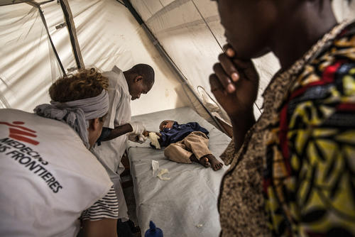 A mother watches her child, who she just brought to the CTC in Katana is examined by MSF nurses for cholera symptoms.