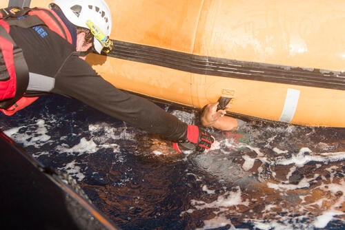 In a nightmarish day on the Mediterranean yesterday, 99 survivors from a sinking rubber boat were rescued by the Aquarius, a search and rescue vessel run by Médecins Sans Frontières (MSF) and SOS MEDITERRANEE, but an unknown number of men, women and children are missing, presumed drowned. Two women are confirmed dead.

“The scene was devastating, with many urgent medical cases in quick succession. They just kept coming, one after another, unconscious and not breathing,” said MSF nurse Aoife Ni Mhurchu. 

Dozens of people were already in the sea when the Aquarius arrived at the scene around 9.30am, and the rubber boat was already deflating. All floating devices were deployed from Aquarius, rafts were launched and the rescue team started pulling people from the sea. 

The MSF medical team on board the Aquarius resuscitated six young children, and one woman. Despite their best efforts they were unable to resuscitate two other women who had drowned. 

“It is absolutely heartbreaking. These women were mothers. We’re now trying to care for their very young children who remain onboard Aquarius” said Ni Mhurchu.

All medical emergencies together with their caretakers were evacuated from Aquarius by an Italian Navy Helicopter to Sfax, Tunisia – a total of sixteen people. This included all six resuscitated children and several women with water on their lungs. The MSF medical team also treated many severe fuel burns, as well as over a dozen mild to moderate hypothermia cases. Many survivors were disorientated and confused as a result of inhaling fuel which had leaked into the rubber boat.