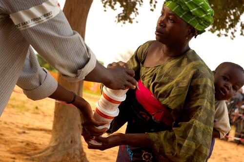 A woman receives a monthly supply of Plumpy'Doz, a ready-to-use supplemental food (RUSF) distributed by MSF, in Guidan Roumji, Niger, August 8, 2007.  During the hunger gap season, when malnutrition rates are typically elevated, mothers are provided with a one month supply of the micro- and mactro-nutrient rich paste.  Children eat three tablespoons of Plumpy'Doz per day with their regular food in order to prevent becoming malnourished. MSF is distributing RUSF to over 60,000 people in Guidan Roumji. On this day, over 1,500 women received rations for their children.