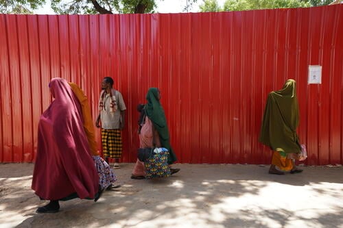 Women and children walk past the outer fence of MSF supported Bay Regional Hospital in Baidoa, Somalia. Reaching healthcare facilities remains a major challenge for women in remote areas and displacement camps, contributing to preventable maternal and newborn deaths.