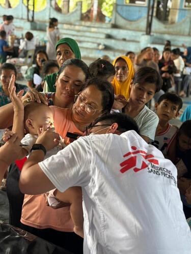 A health worker attends to a child at a mobile clinic set up inside a covered basketball court in Sarangani Province, Mindanao, Philippines. For remote communities still largely unreached, these mobile clinics are a critical lifeline, providing essential care amid ongoing aftershocks that continue to disrupt access to basic health services.