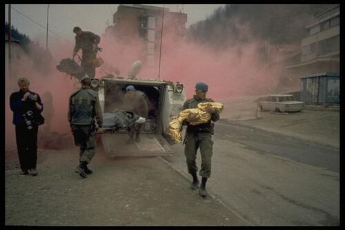 A peacekeeper carries to safety a child in a thermal blanket. Thousands of civilians flee the bombing of Srebrenica, 6000 people were reported missing, Bosnia 1995