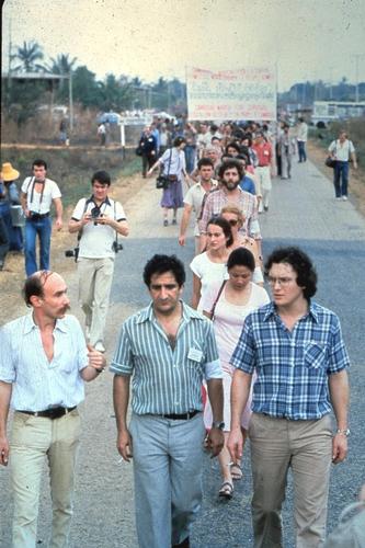 6 Fevrier 1980.
<br/>Claude Malhuret,president de MSF France de 1978 a 1979, Xavier Emmanuelli, president de 1979 a 1980, et Rony Brauman, president de 1982 a 1994, pendant la "Marche pour la survie du Cambodge", a la frontiere entre le Cambodge et la Thailande, pres d'Aranya-Prathet. 
<br/>En tête de la marche, une banderole en 3 langues : "Cambodge, marche pour la survie. Permettez-nous d'aider le peuple khmer."
<br/>Claude Malhuret, president of MSF France from 1978 to 1979, Xavier Emmanuelli, president from 1979 to 1980, and Rony Brauman, president from 1982 to 1994 during the 'march for the survival of Cambodia', on the Thai border in 1980.